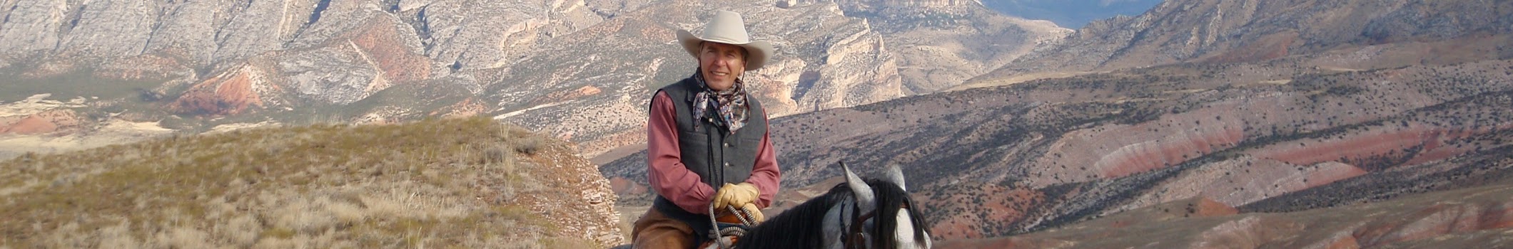 Mark Bedor of Today's Wild West riding on horseback in an expansive valley with a mountainous landscape behind him.